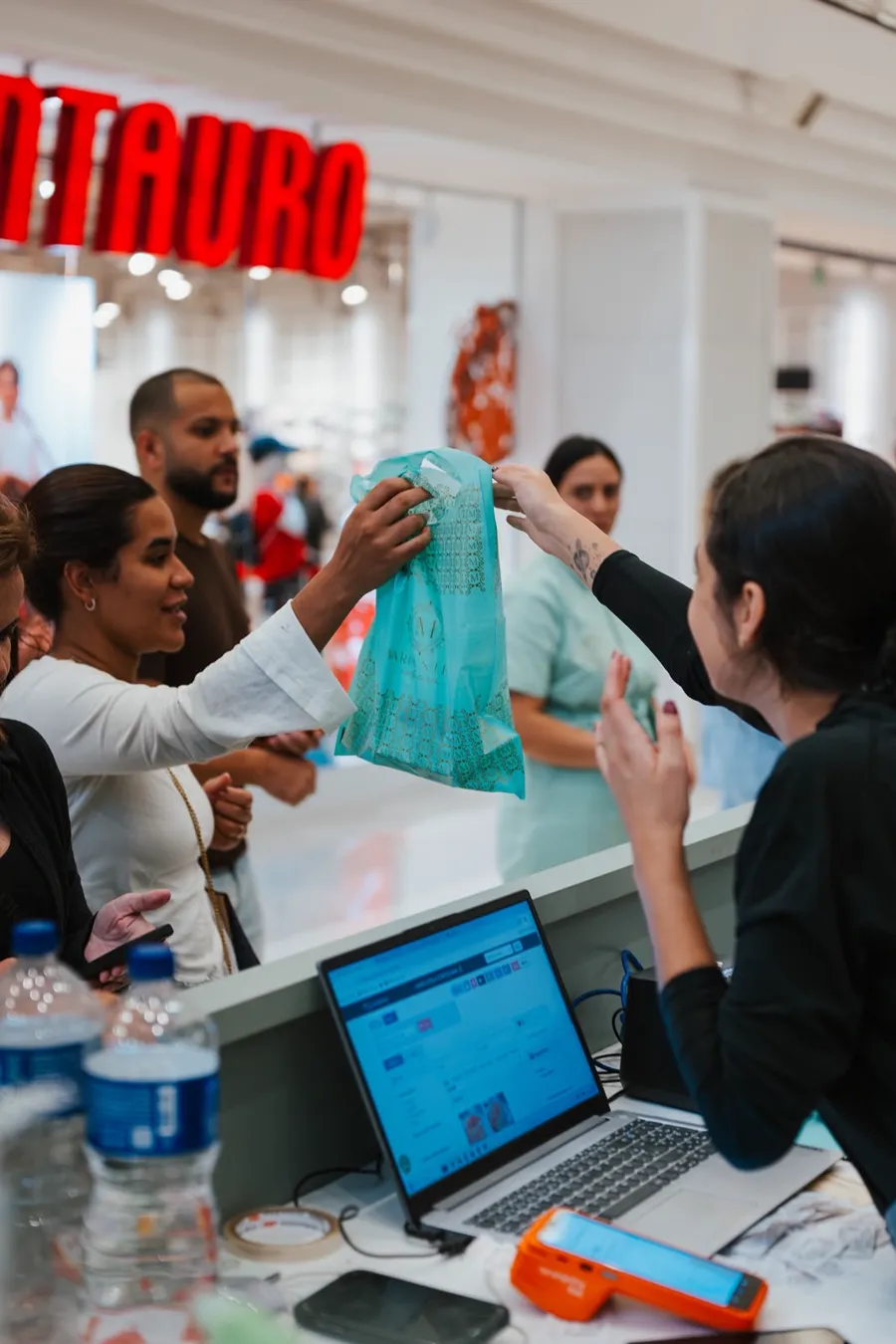 Cliente recebendo sacola Maria Stela no quiosque
